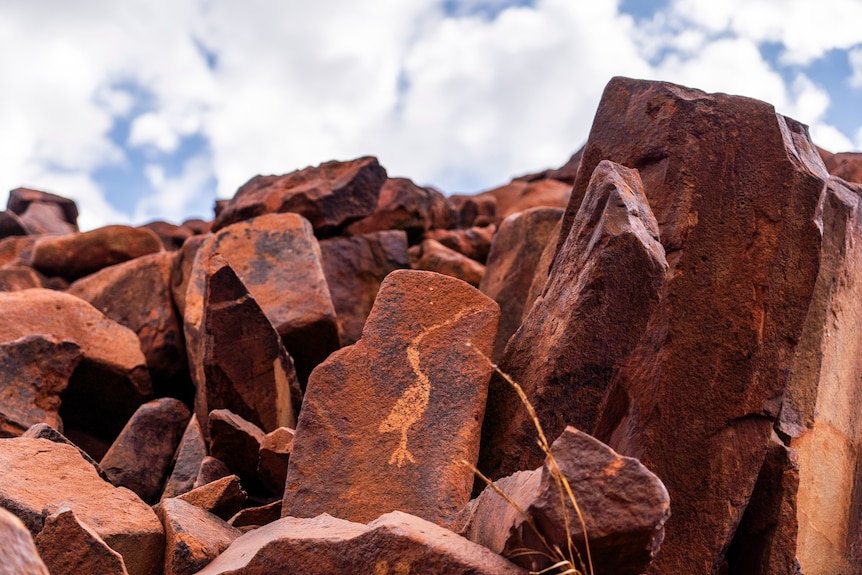 ancient engravings on red rocks surrounded by many other red rocks in the landscape