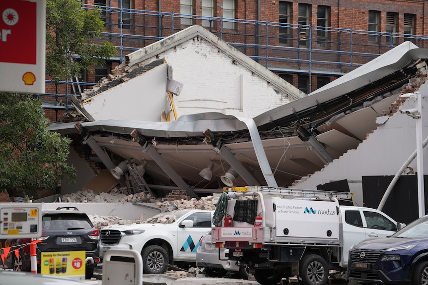 A biodlung next to a petrol station collapsed with rubble on nearby parked cars.