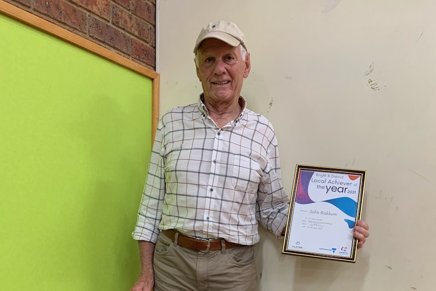 A man standing showing a certificate in his hand
