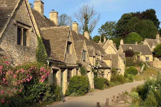 A row of Cotswold stone cottages along a lane in the village of Bibury in the Cotswolds early on a summer’s morning