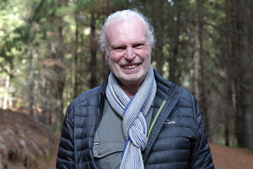 Man with scarf and puffer jacket, in forest.