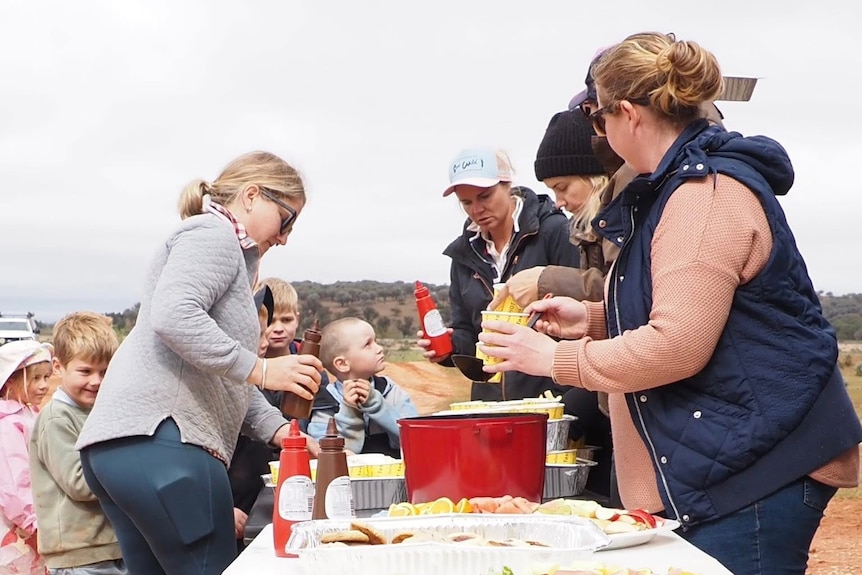Station kids and parents gather to share a meal in the bush