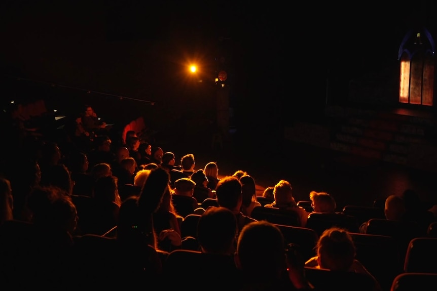 A view of a crowd of people sitting in seats at a theatre.
