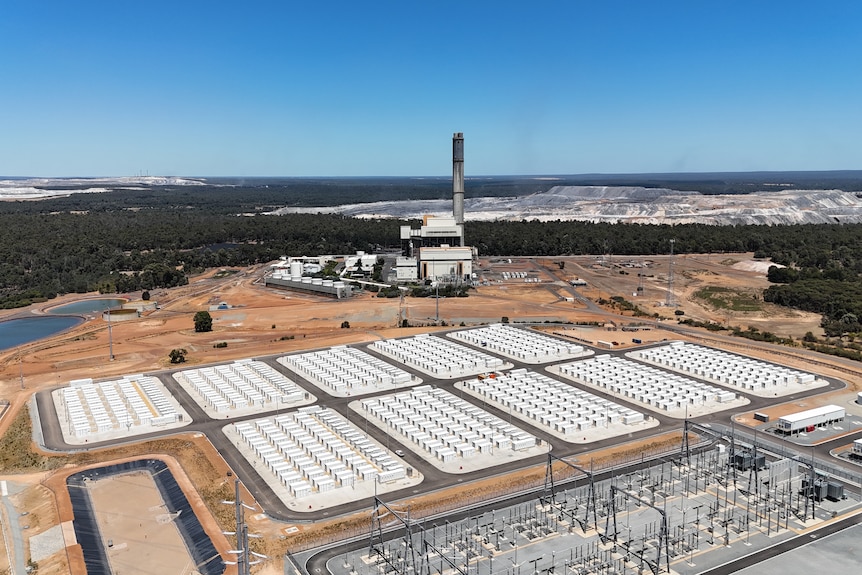 Drone shot of big battery in the foreground, coal plant in the mid ground and coal mine in background