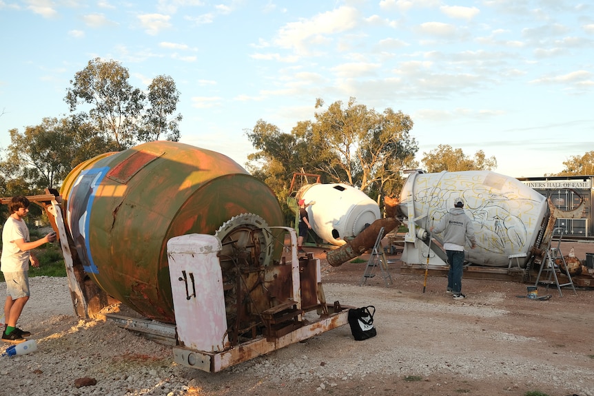 Two mining agitators that used to sift soil for opal miners are painted with a base coat before the artists paint their mural