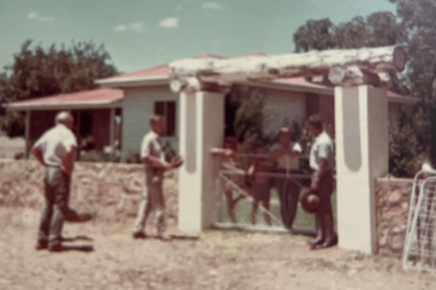 Old photo of men meeting at the front gate of a rural homestead