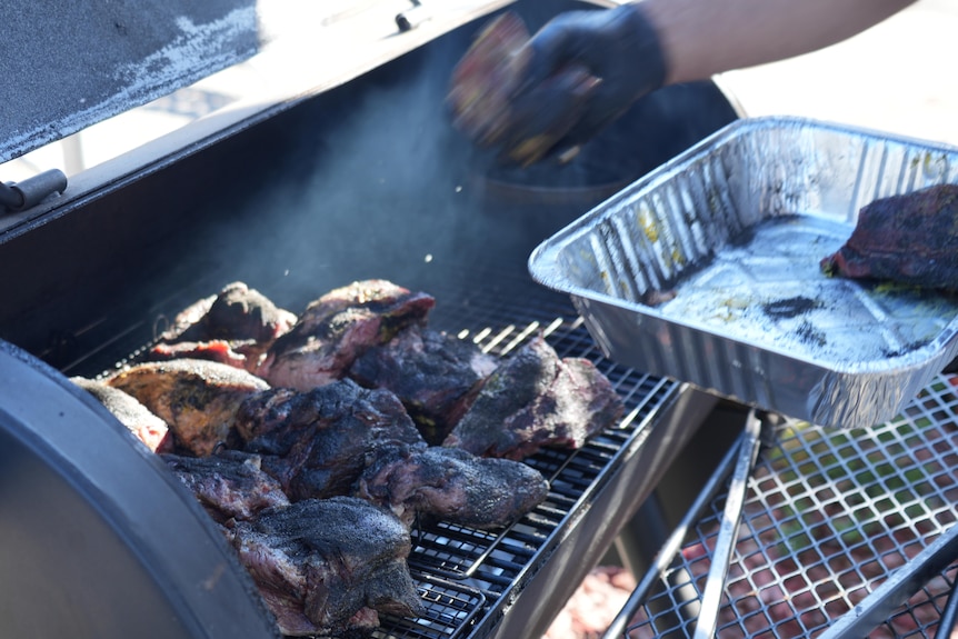 An open smoker barbecue with well seasoned beef on the grill
