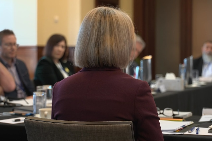 The back of a woman's head who is seated at a round table
