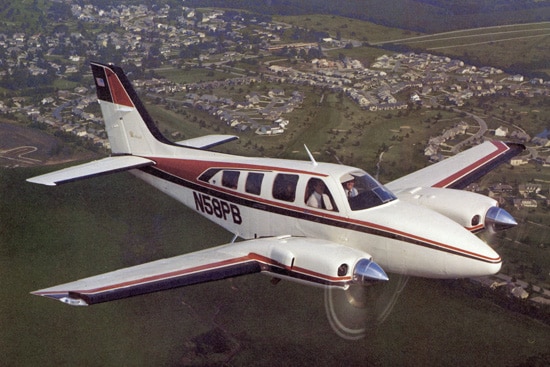 White Beechcraft Baron 58 plane with red and white stripes in the sky
