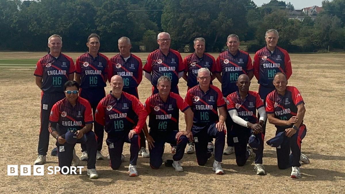 The 2026 England Over-60s World Cup squad looking towards the camera with barren grass in the foreground and green trees in the background.