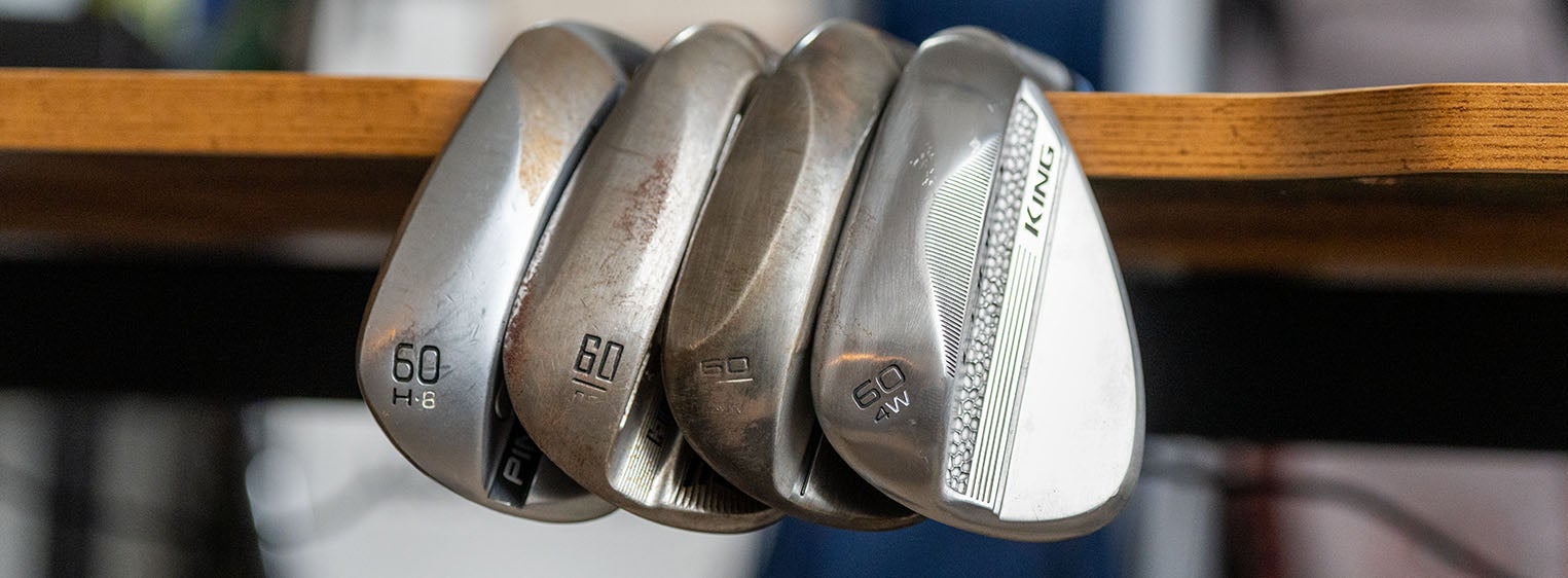 Four perfect wedges sit side by side on the edge of a wooden table, showing their club faces and loft numbers, including two marked 60—each one Fully Fit 2026 for exceptional precision on the course.