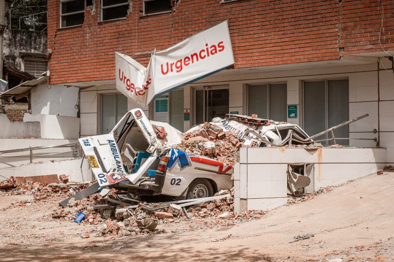 An ambulance crushed by falling debris from the “Clinica Nuestra” private hospital in Cali, which partially collapsed during the August 10 earthquake. [Euan Wallace / Al Jazeera]