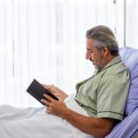 Caucasian mid adult patient writing a diary while recovering in the hospital ward - stock photo