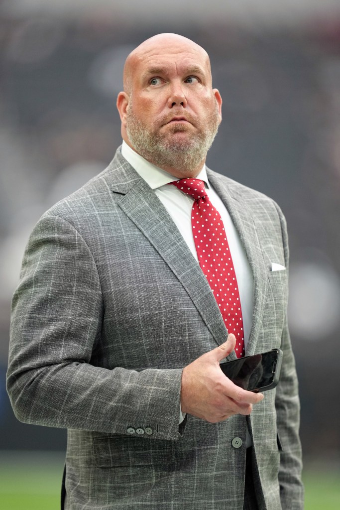 Steve Keim, former general manager of the Arizona Cardinals, stands on the field wearing a suit.
