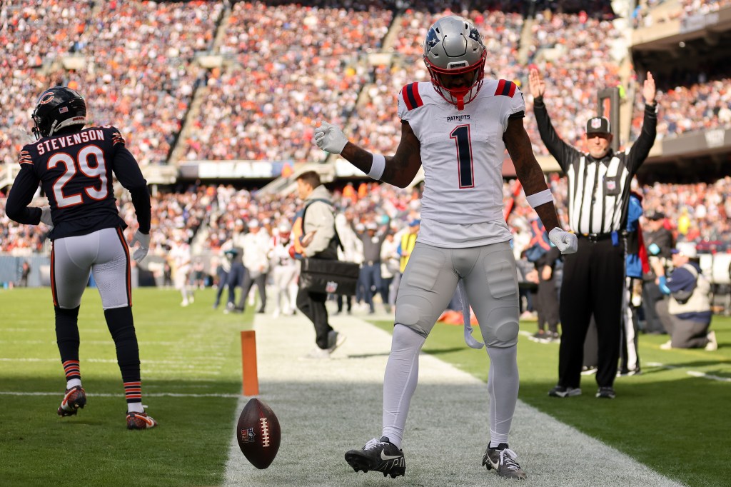 New England Patriots player #1 celebrates a touchdown with a football floating nearby, while Chicago Bears player Stevenson #29 walks away.