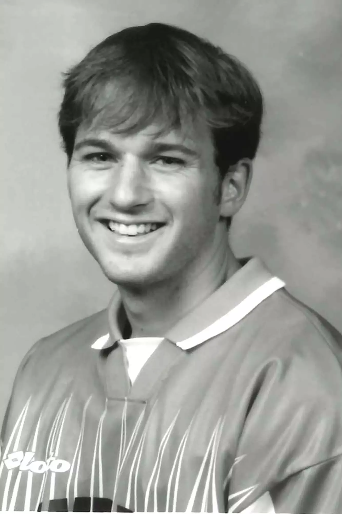 Headshot of a man smiling while wearing a soccer jersey.