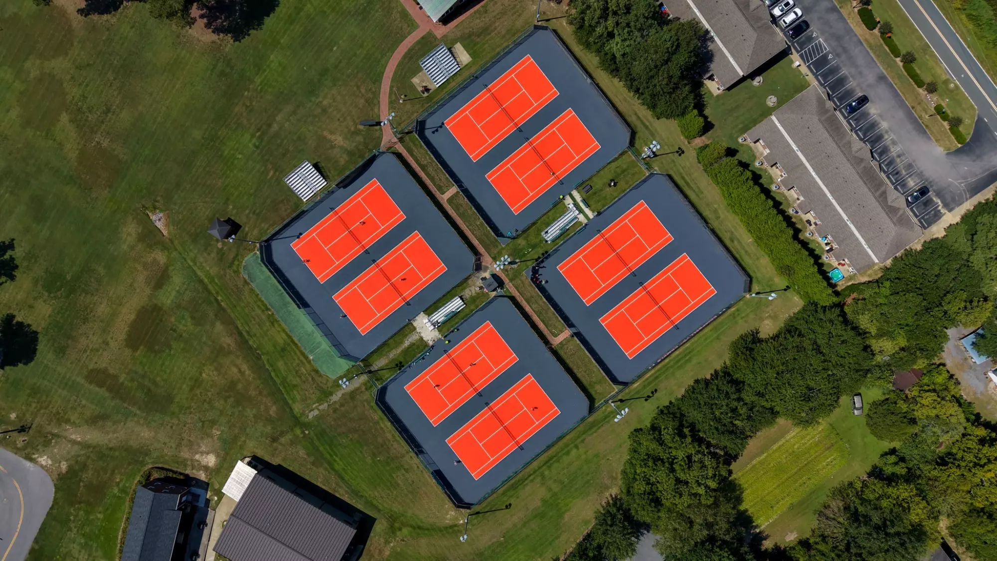 Aerial view looking directly down at the Nisbet Tennis Center's newly resurfaced orange and slate gray tennis courts.