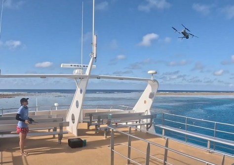 A person launching a drone from a boat to conduct a reef survey