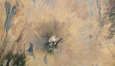 Satellite picture of a dry region with a volcano capped with white ash