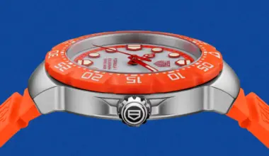 Silver TAG Heuer Formula 1 watch with orange bezel and strap on blue background.