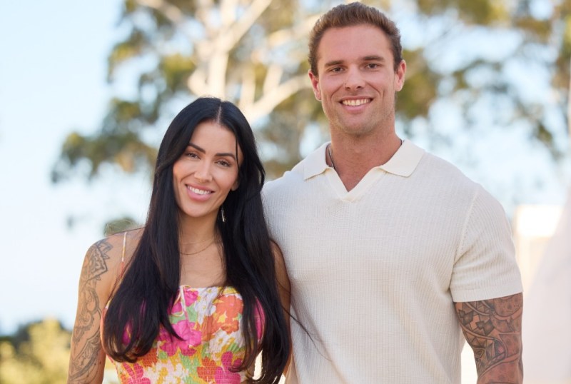 Smiling couple standing outdoors with trees in the background, showcasing their style and connection, featured on "The Block" page.