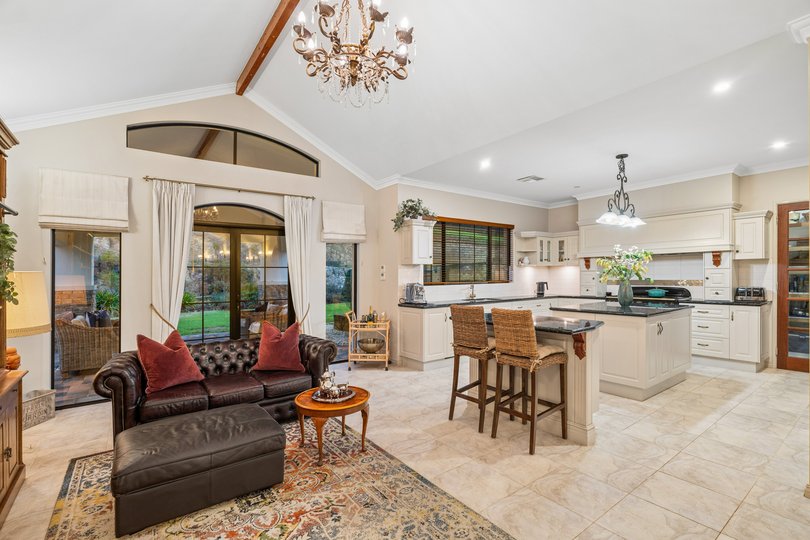 The kitchen flows seamlessly from the main space, featuring stone benchtops and a freestanding range cooker.