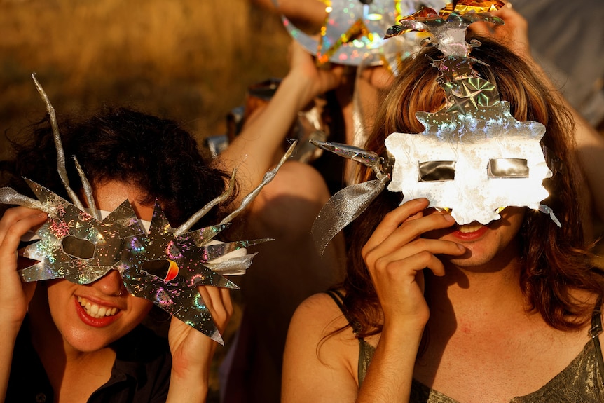 Two women wear hand made masks for the solar eclipse.