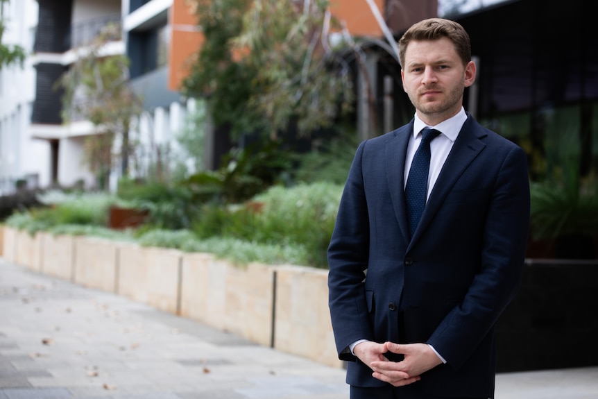 A man wearing dark blue suit standing on an empty street.