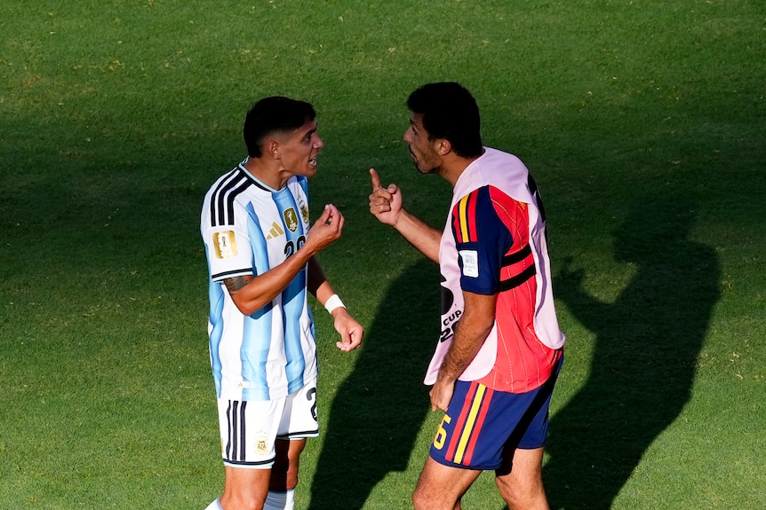 Two football player angrily confront each other.