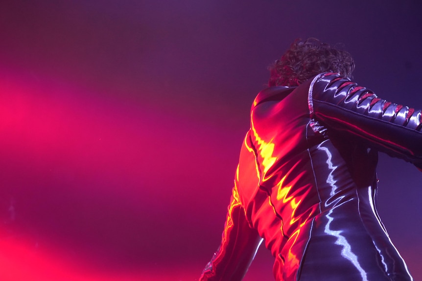 A man in a shiny leather jacket under red light