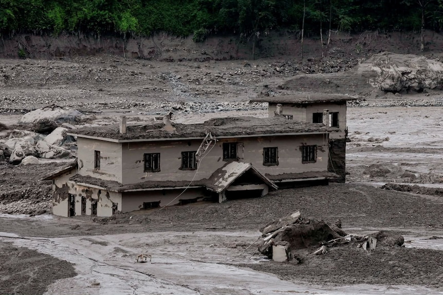 The first storey of a house sits below the line of mud.