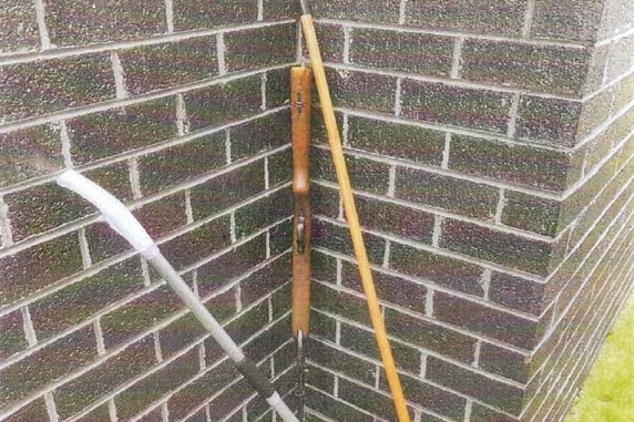 An air rifle, next to a brick wall