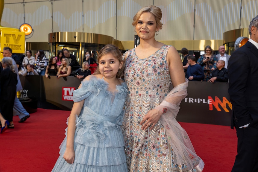Hart wears a powder blue tiered tulle dress and McGuire wears a scoop neck A-line dress with colourful embroidery.