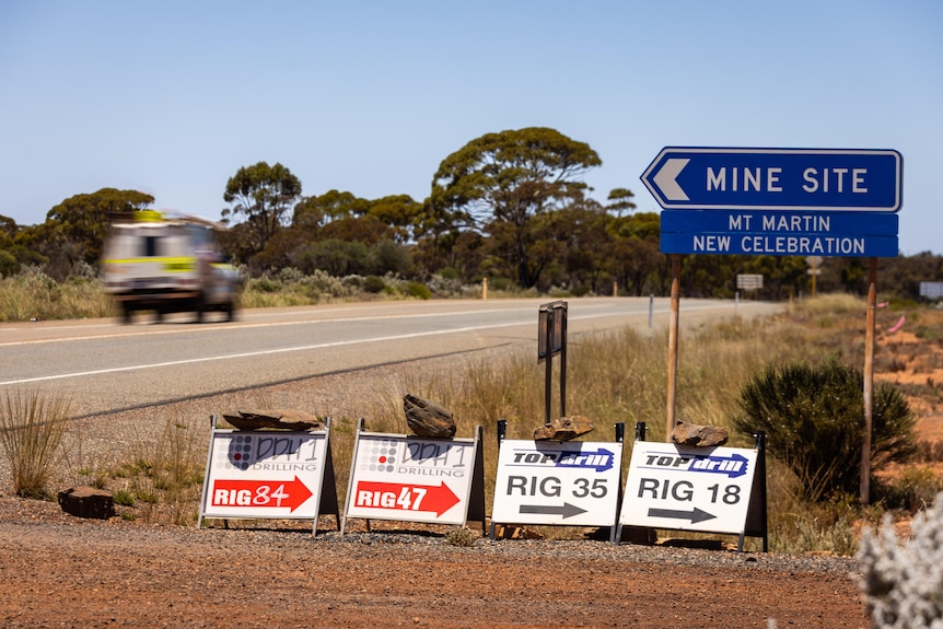 A vehicle drives along an outback highway near a sign that says "Mine site".
