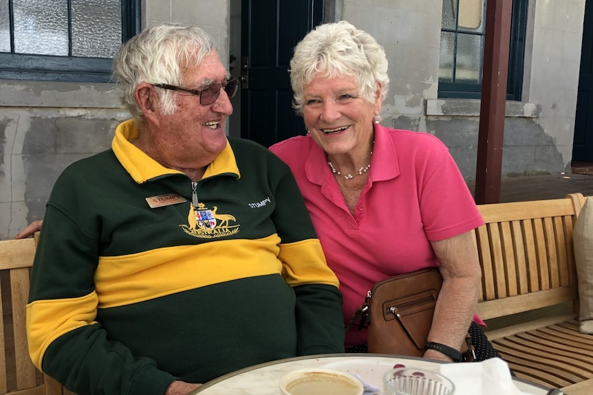 A couple with grey hair sitting together smiling.