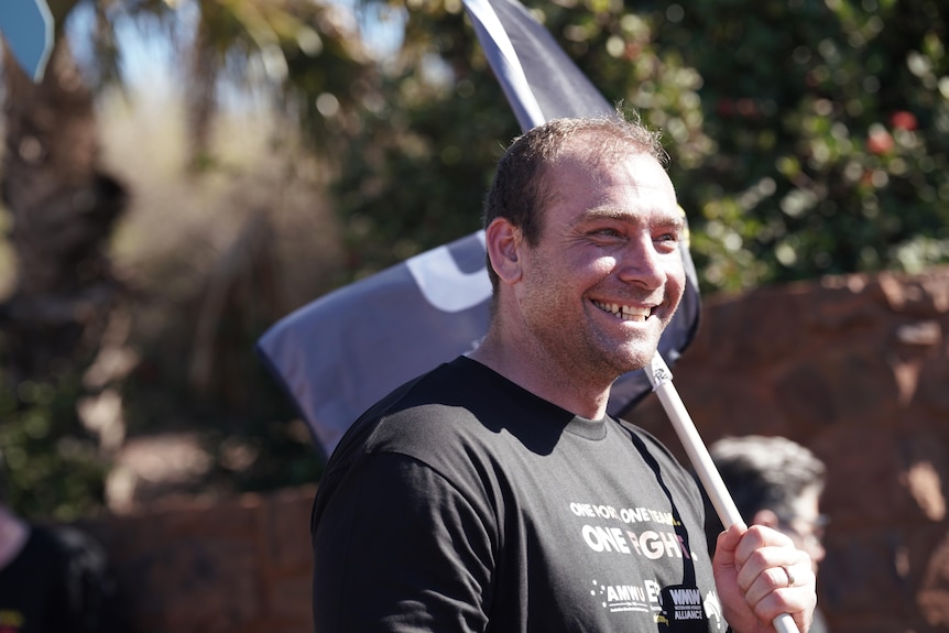 A man wearing black T-shirt has a flag pod on his left shoulder.