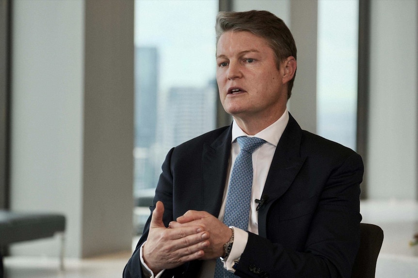 Ben Carroll in a suit and tie looking towards a journalist