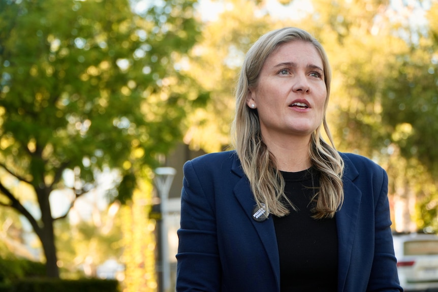 Sophie McNeill wears her blonde hair out and a blue blazer as she is pictured in a park