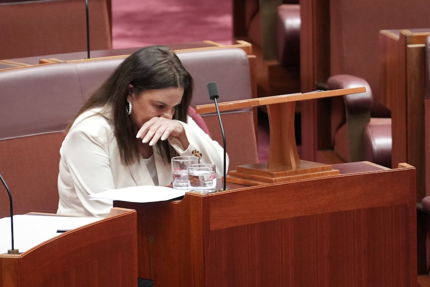 A woman dries her tears while seated in parliament