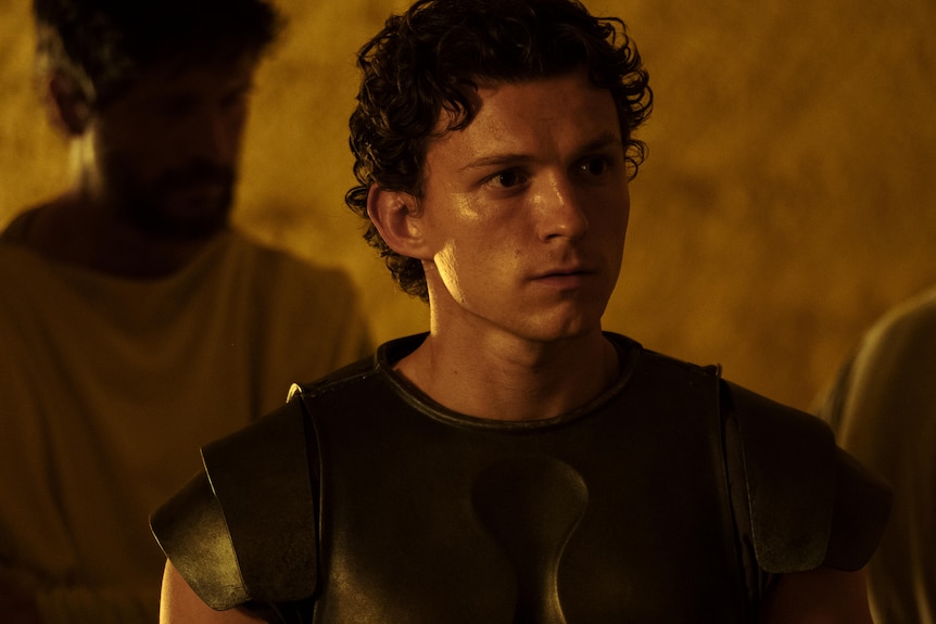 Tom Holland - a young man, brown hair with a serious expression on his face in character in a screen grab from movie