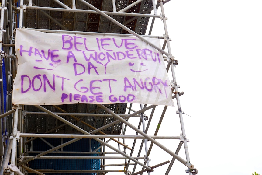 A sign saying 'Have a wonderful day' is attached to scaffolding poles
