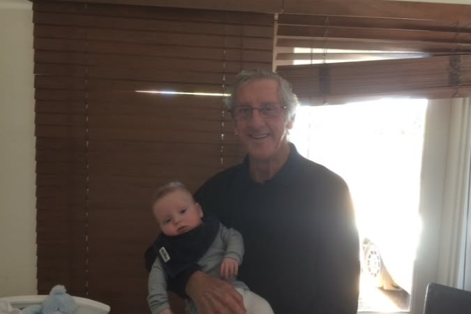 An older man holding a toddler in his arms.