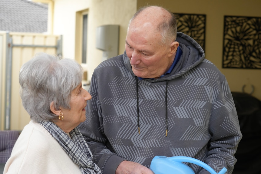 A man and a woman talk while watering plants.