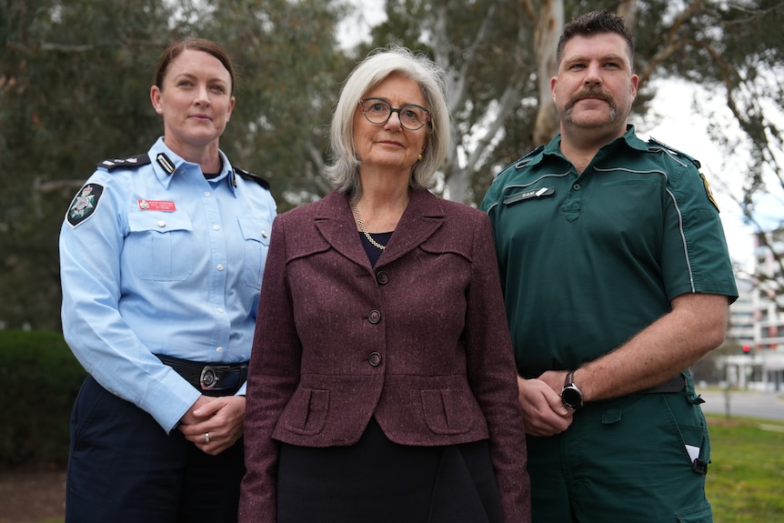 A police woman, a government health executive and a parademic stand together.