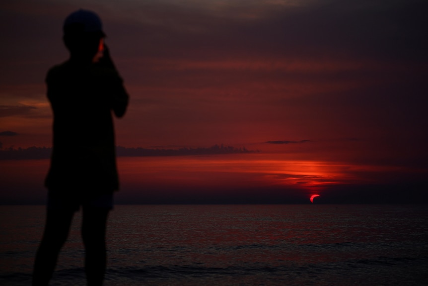 A person filming a red sky line.