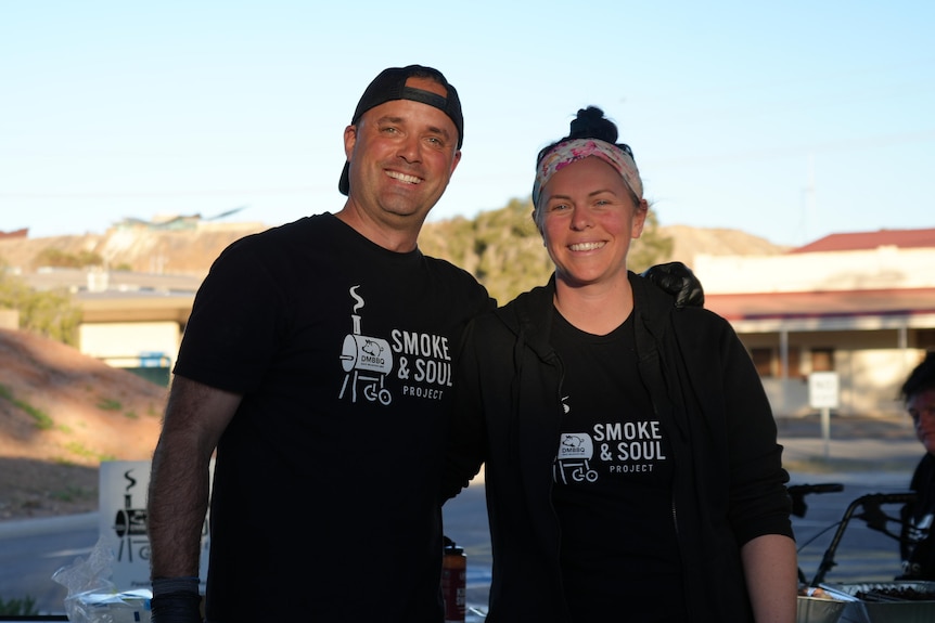 A man and a woman with Smoke and Soul T-Shirts stand smiling with their arms around each other