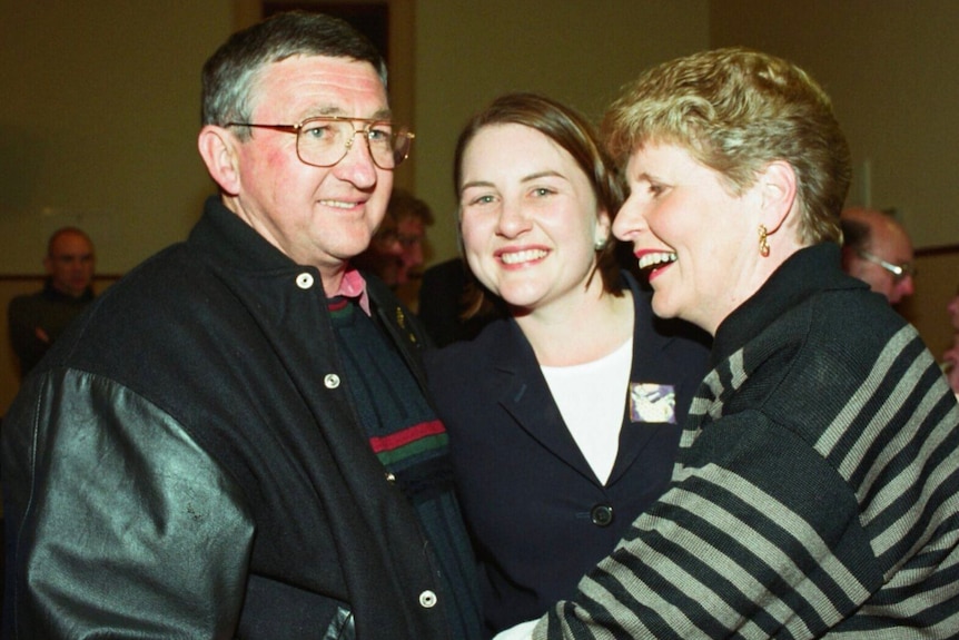 A man and a woman hug a young woman.