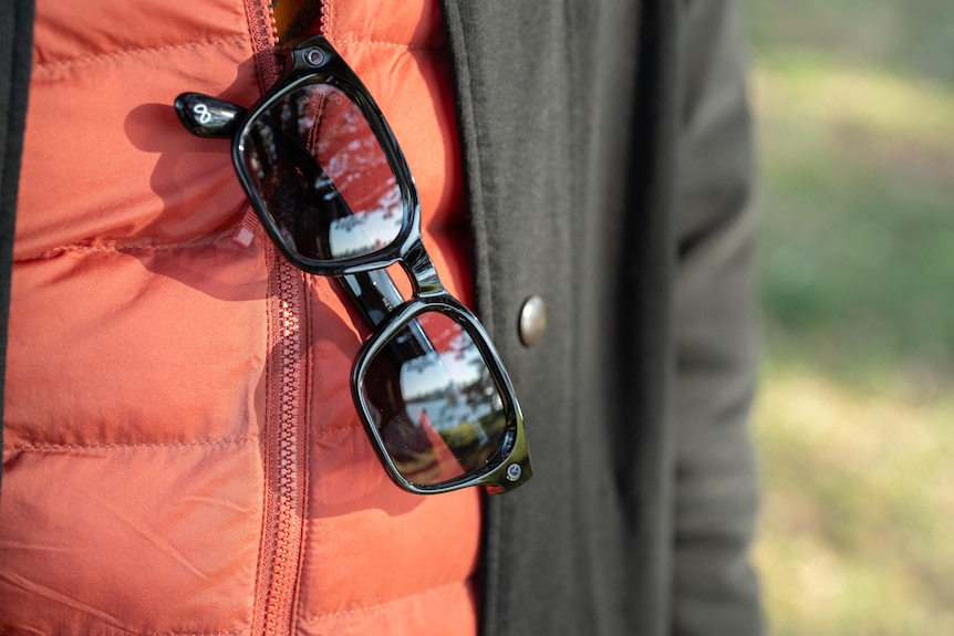 A pair of smart glasses are carried on person's jacket.