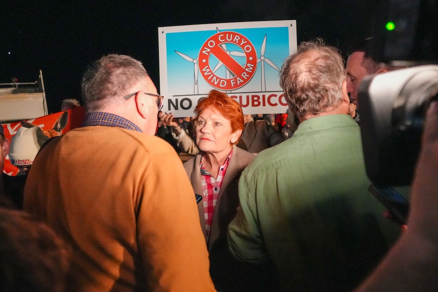 Pauling Hanson outside at night speaking with men at an event.