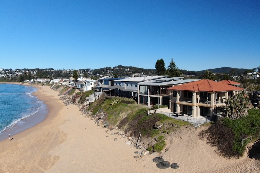 Aerial shot of a section of coastline with properties that have been impacted by coastal erosion.